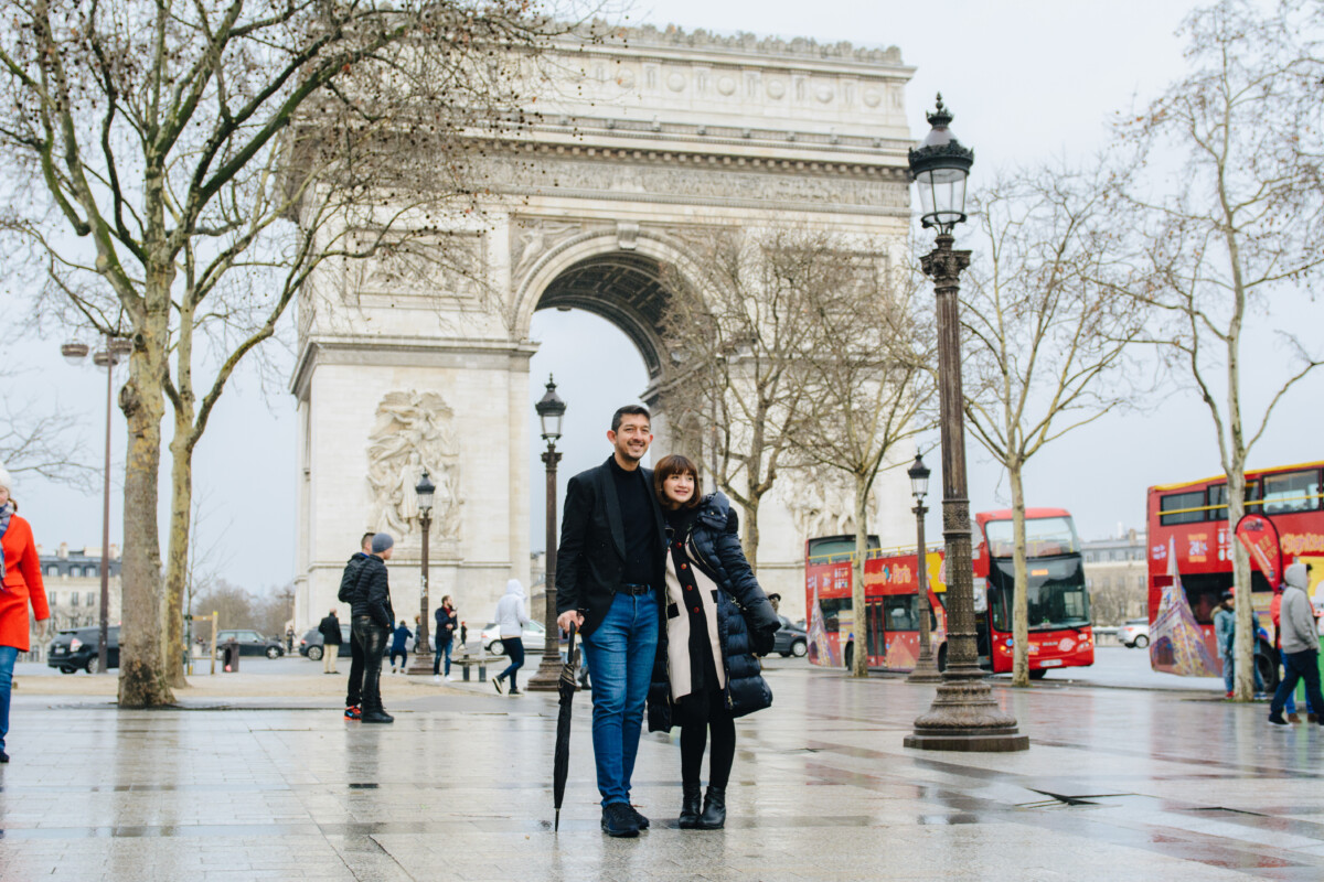 Honeymoon couple walking at champs Elysee, background Arc de Triomphe Paris. Photosession by Eny Therese Photography
